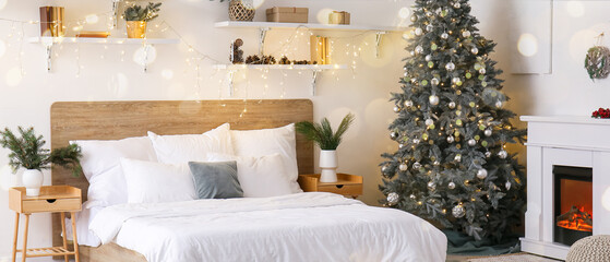 Interior of light bedroom with Christmas tree, fireplace and glowing lights