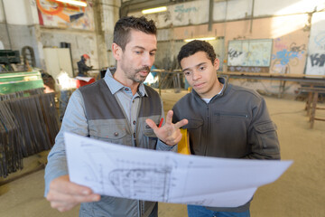 engineer explaining his blueprint to the factory staff