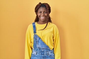 African woman standing over yellow background with a happy and cool smile on face. lucky person.