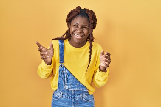 African woman standing over yellow background celebrating mad and crazy for success with arms raised and closed eyes screaming excited. winner concept