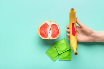 Woman with banana, grapefruit and condoms on green background. Sex concept