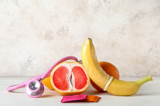 Fruits with stethoscope and condoms on beige background. Sex concept