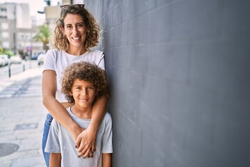 Mother and son smiling confident hugging each other at street