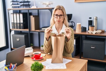 Young caucasian woman working at the office holding paper bag depressed and worry for distress, crying angry and afraid. sad expression.