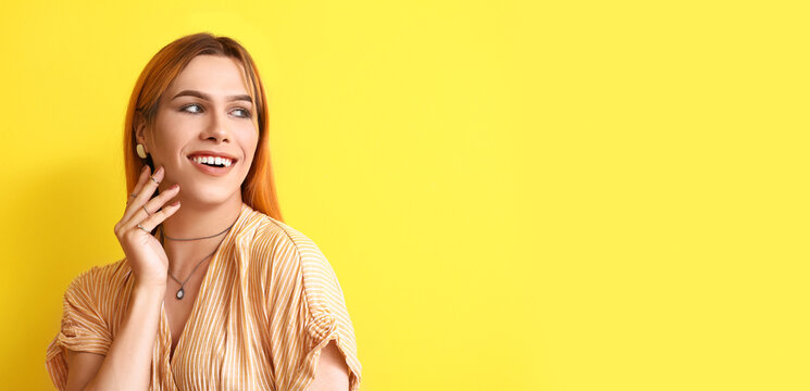 Young transgender woman with beautiful manicure on yellow background