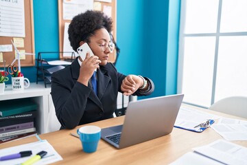 African american woman business worker talking on smartphone looking watch at office