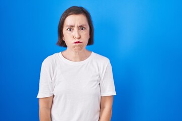 Middle age hispanic woman standing over blue background puffing cheeks with funny face. mouth inflated with air, crazy expression.