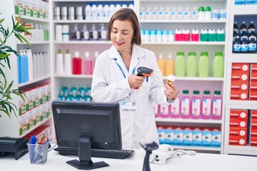 Middle age woman pharmacist scanning pills bottle at pharmacy