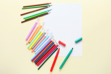 Blank paper sheet with pencils and felt-tip pens on beige background