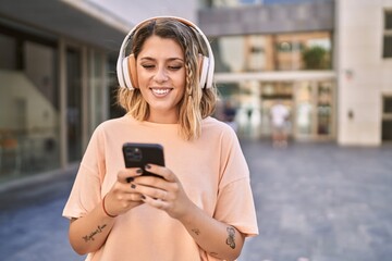 Young hispanic woman smiling confident listening to music at street