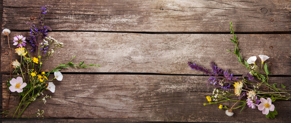 Wild flowers on old grunge wooden background (chamomile lupine dandelions thyme mint bells rape)