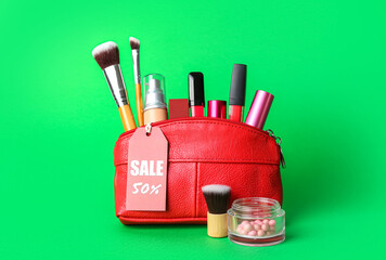 Bag with cosmetic products, accessories and sale tag on green background