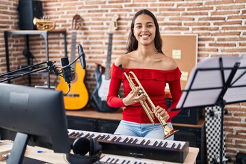 Fototapeta na wymiar Young african american woman musician playing trumpet at music studio
