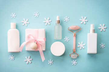 Natural cosmetic with holiday decorations on blue. Winter scincare concept. Flat lay image.