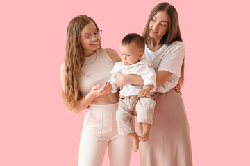 Happy lesbian couple with their little baby on pink background