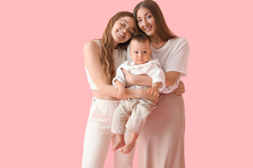 Happy lesbian couple with their little baby on pink background