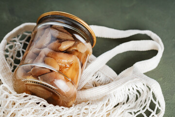 Jar of pickled mushrooms in a mesh bag. Zero waste concept with canned mushrooms and string bag. Top view