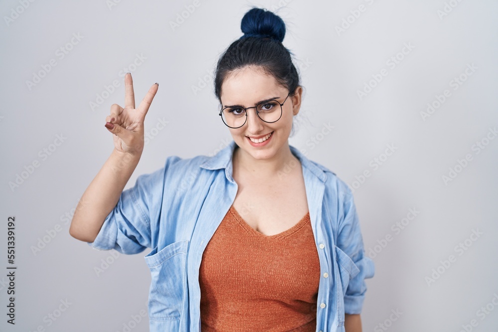 Poster young modern girl with blue hair standing over white background showing and pointing up with fingers