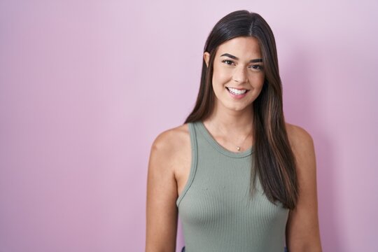 Hispanic woman standing over pink background with a happy and cool smile on face. lucky person.