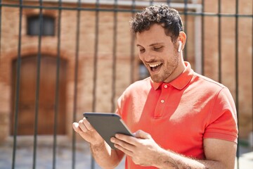 Young hispanic man watching video on touchpad at street