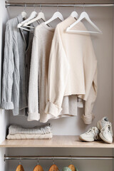 Warm knitted sweaters hanging in wardrobe