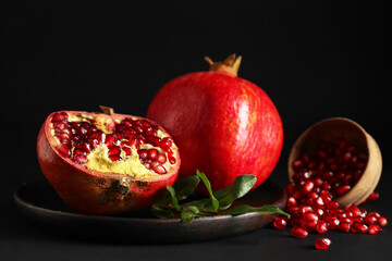 Plate with fresh ripe pomegranates on dark background, closeup