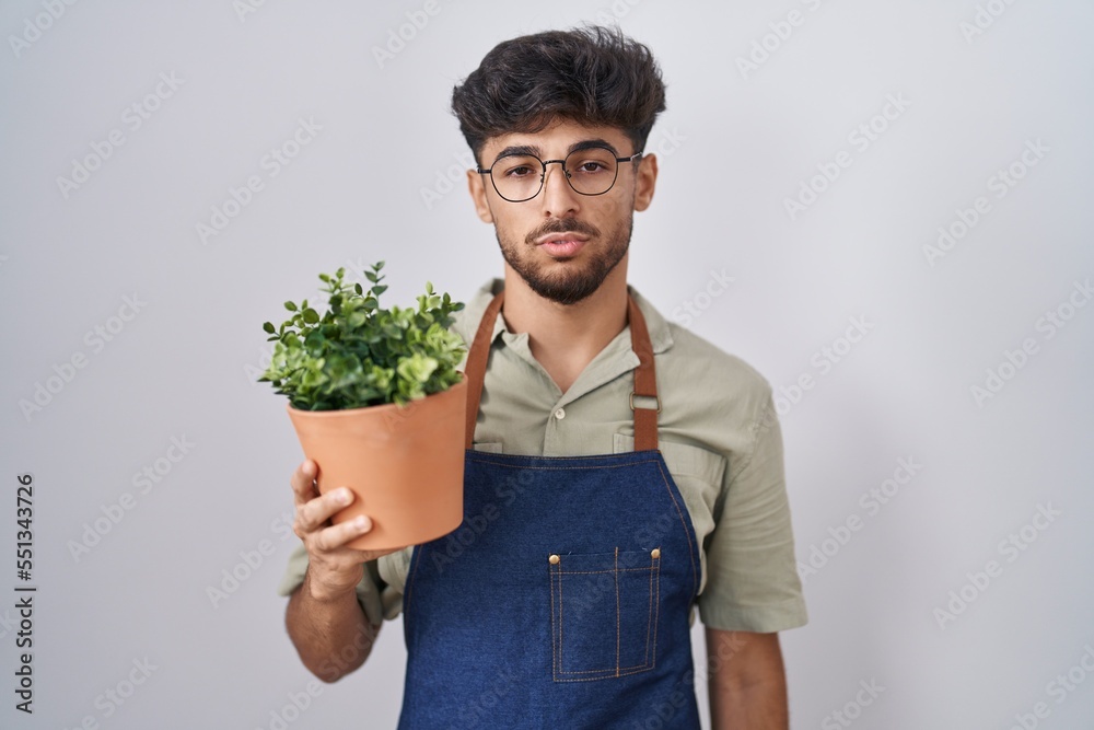 Sticker arab man with beard holding green plant pot looking sleepy and tired, exhausted for fatigue and hang