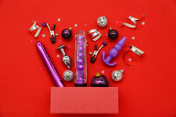 Gift box with sex toys and Christmas decor on red background