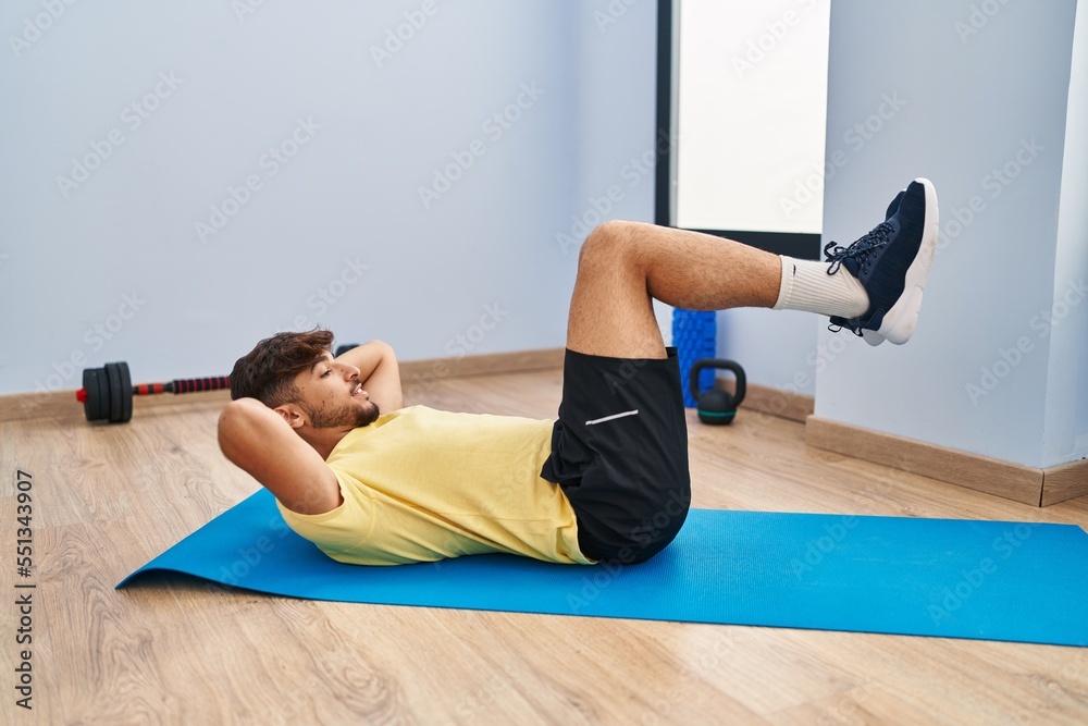 Sticker Young arab man training abs exercise at sport center