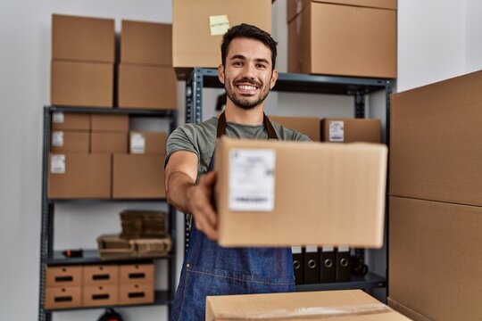 Young hispanic man business worker holding package at storehouse