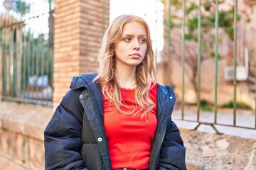 Young blonde woman looking to the side with serious expression at street