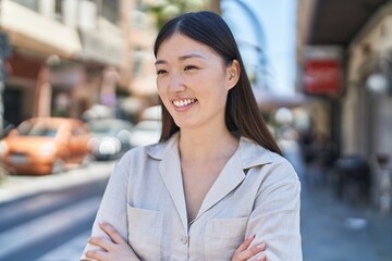 Chinese woman smiling confident standing with arms crossed gesture at street