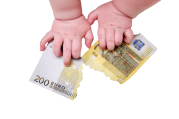 Baby hand and torn money in euros, close-up, isolated on a white background. Children fingers and an object on a white background