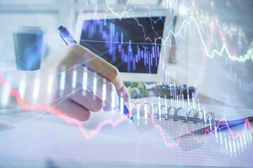 Financial forex graph drawn over hands taking notes background. Concept of research. Multi exposure