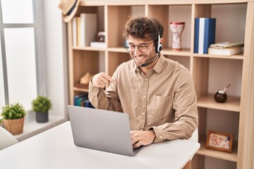 Hispanic young man wearing call center agent headset pointing finger to one self smiling happy and proud