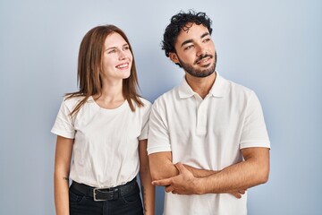 Young couple wearing casual clothes standing together looking away to side with smile on face, natural expression. laughing confident.
