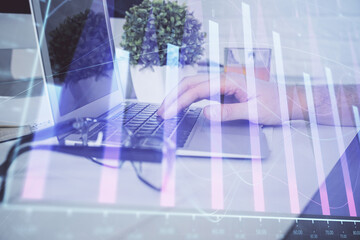 Multi exposure of graph with man typing on computer in office on background. Concept of hard work. Closeup.