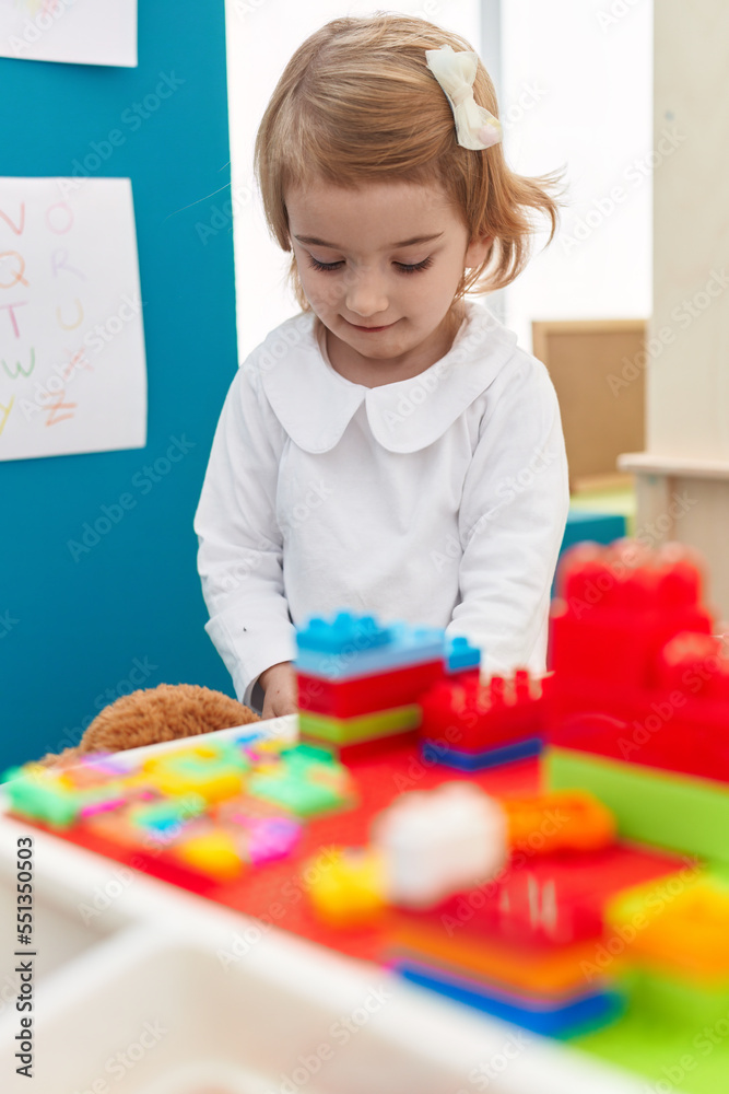 Sticker adorable caucasian girl playing with construction blocks standing at kindergarten