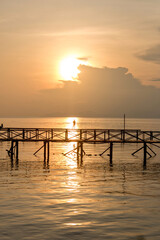 Fototapeta na wymiar Silhouette of man fishing on jetty on mabul island at sunset in borneo