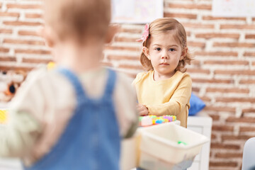 Obraz premium Adorable hispanic girl playing with construction blocks standing at kindergarten