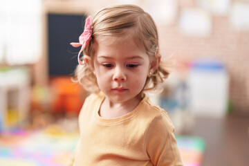 Adorable hispanic girl standing with relaxed expression at kindergarten