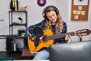 Young woman musician playing classical guitar at music studio