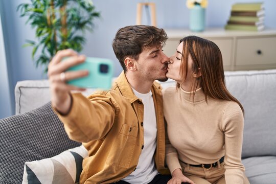 Mand and woman couple make selfie by smartphone sitting on sofa at home