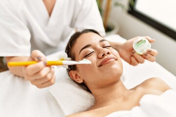 Obraz na płótnie Canvas Young latin woman relaxed having skin face aloe vera treatment at beauty center