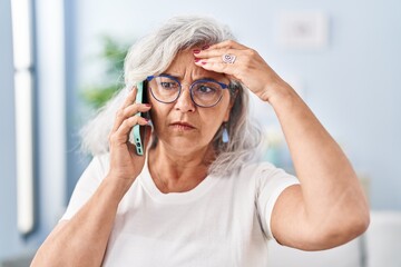 Middle age woman worried talking on the smartphone at home - obrazy, fototapety, plakaty