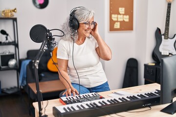 Middle age woman musician playing keyboard piano at music studio