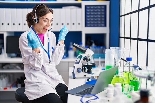 Hispanic woman working at scientist laboratory screaming proud, celebrating victory and success very excited with raised arms