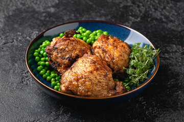 Baked Chicken thighs with green peas in blue plate