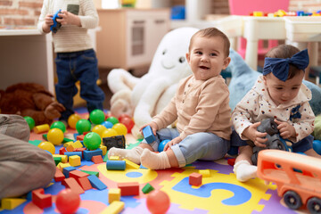 Two toddlers playing with toys sitting on floor at kindergarten