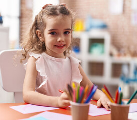 Adorable caucasian girl playing with construction blocks sitting on table at classroom